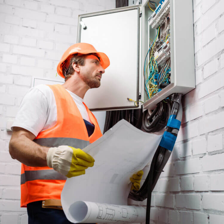 Handsome Electrician Holding Blueprint And Looking At Electrical